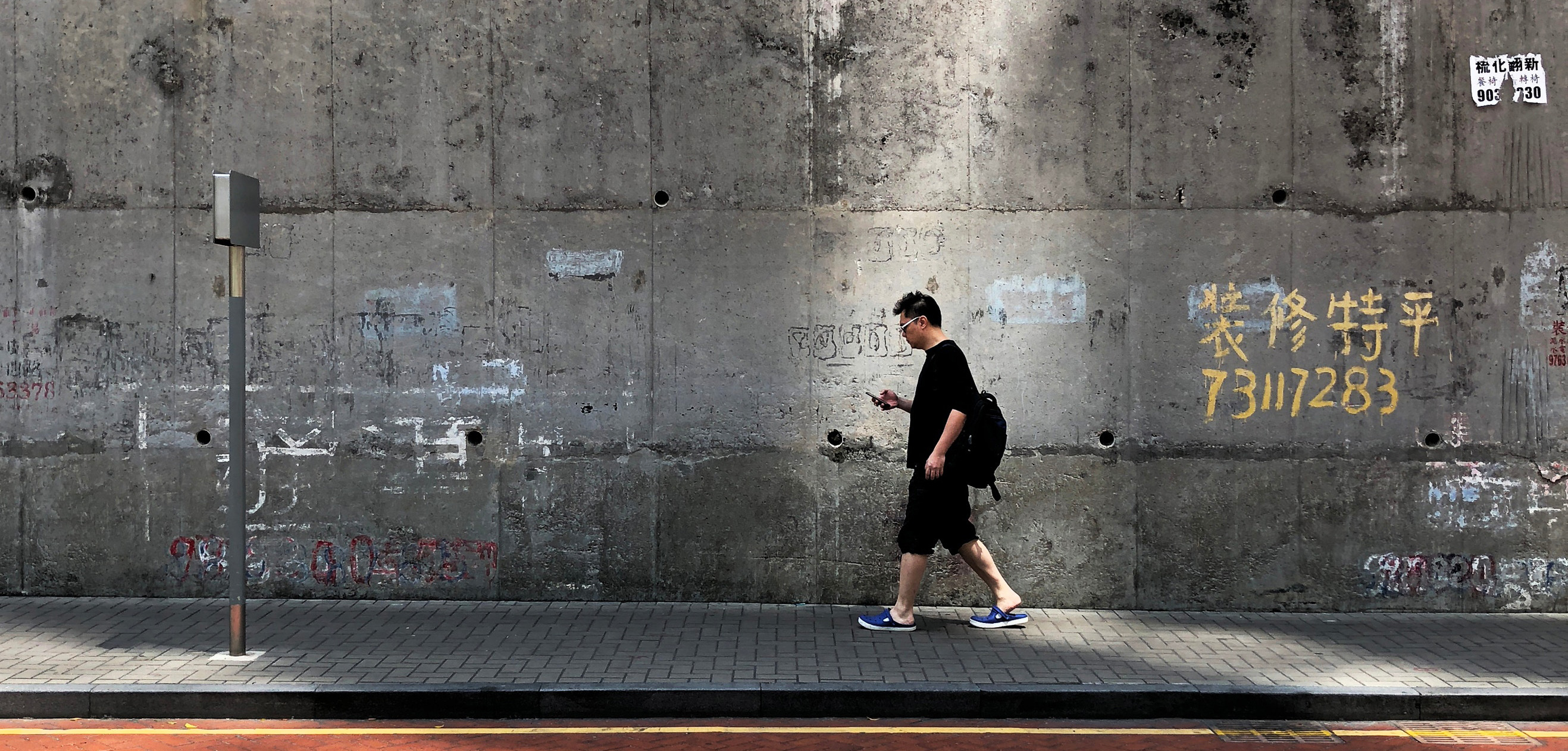 Man walking on pavement using a phone