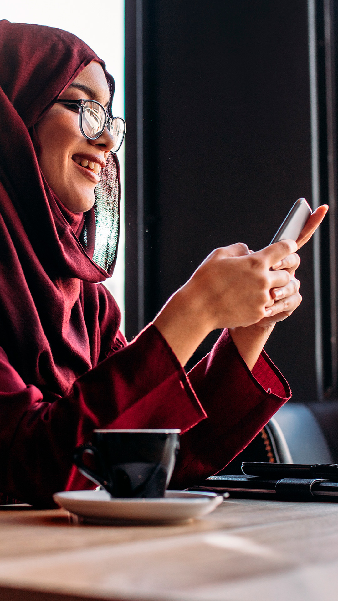woman smiling at phone at coffee shop