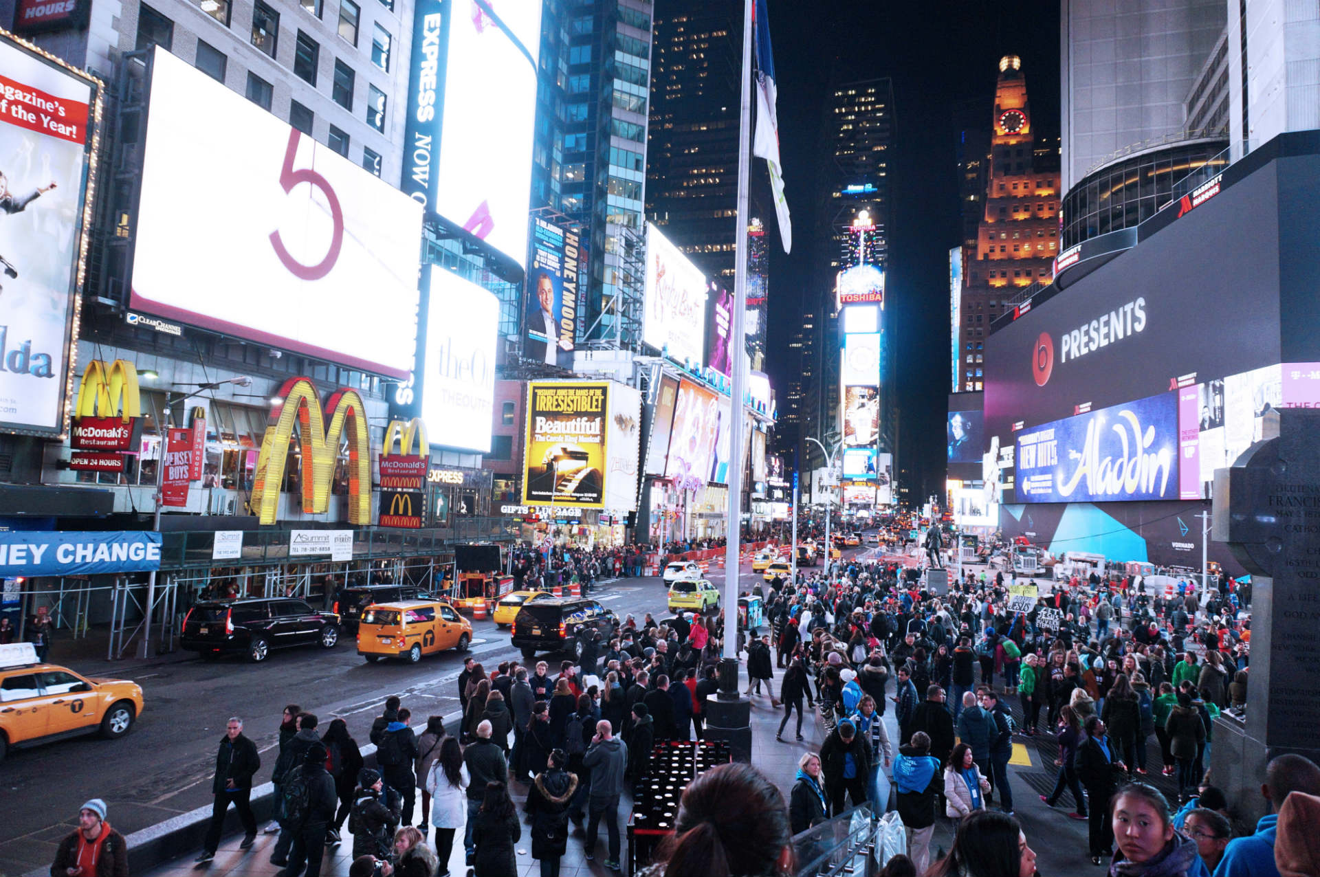 a city square full of lights and crowds of people