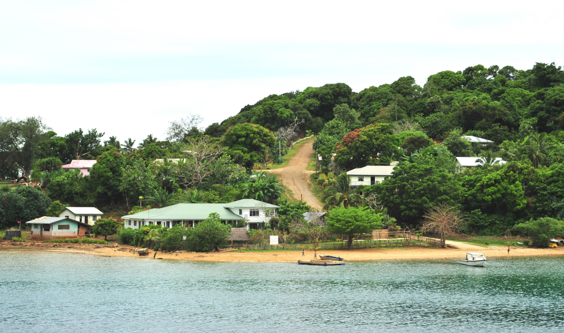 dirt track road leaving to small houses dotted round a beach