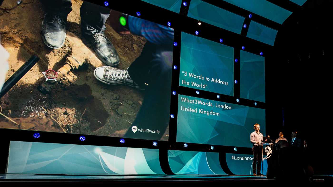 man giving speech with slideshow in background