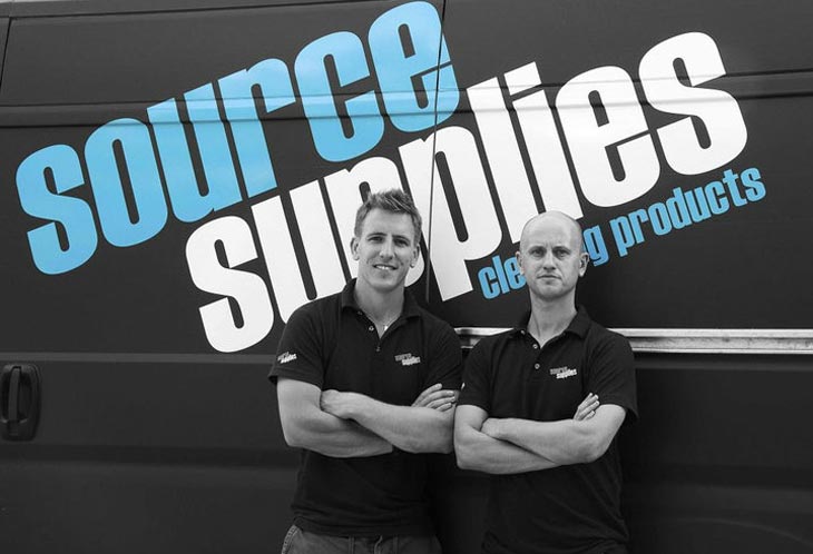 two men pose in front of company cleaning van