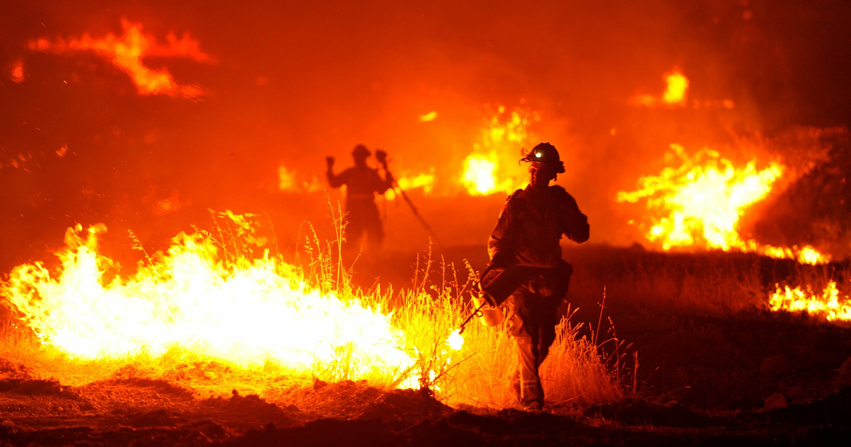 firefighters fighting a blazing fire in a field