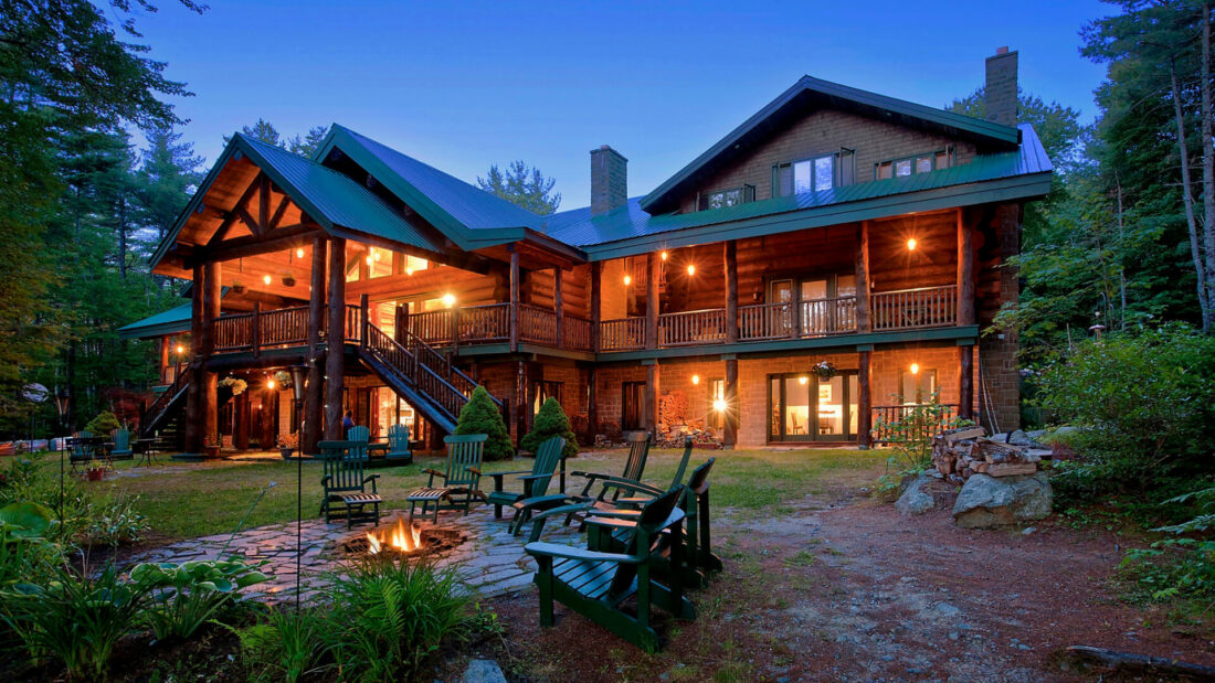 wooden lodge with garden and chairs around a fire 