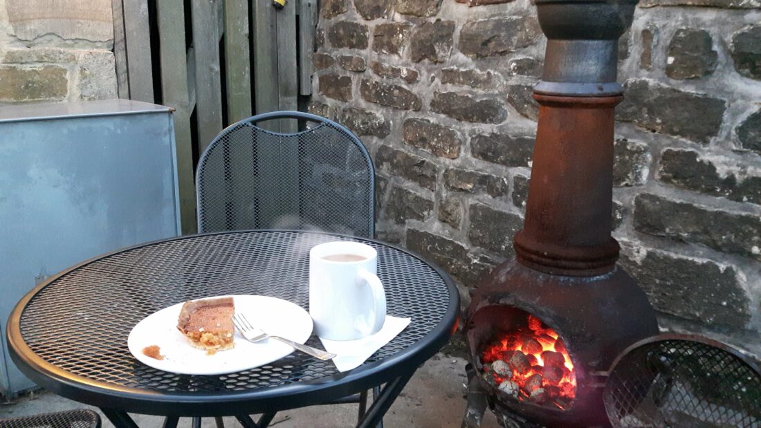 Table with coffee and cake on it with fire heater in the background