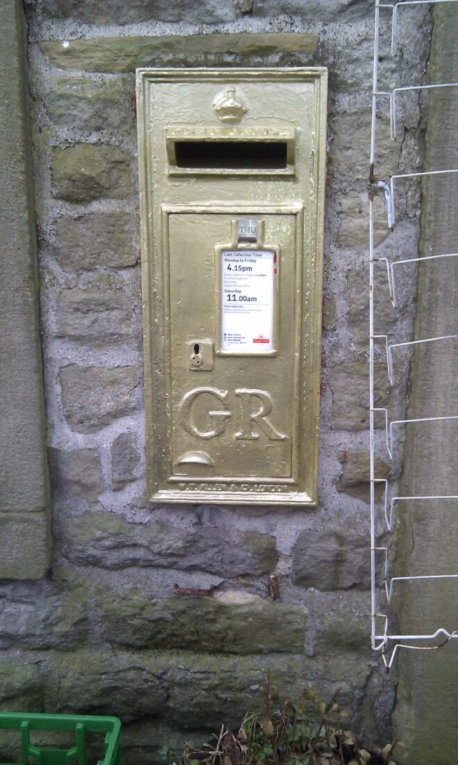 Gold postbox in a brick wall